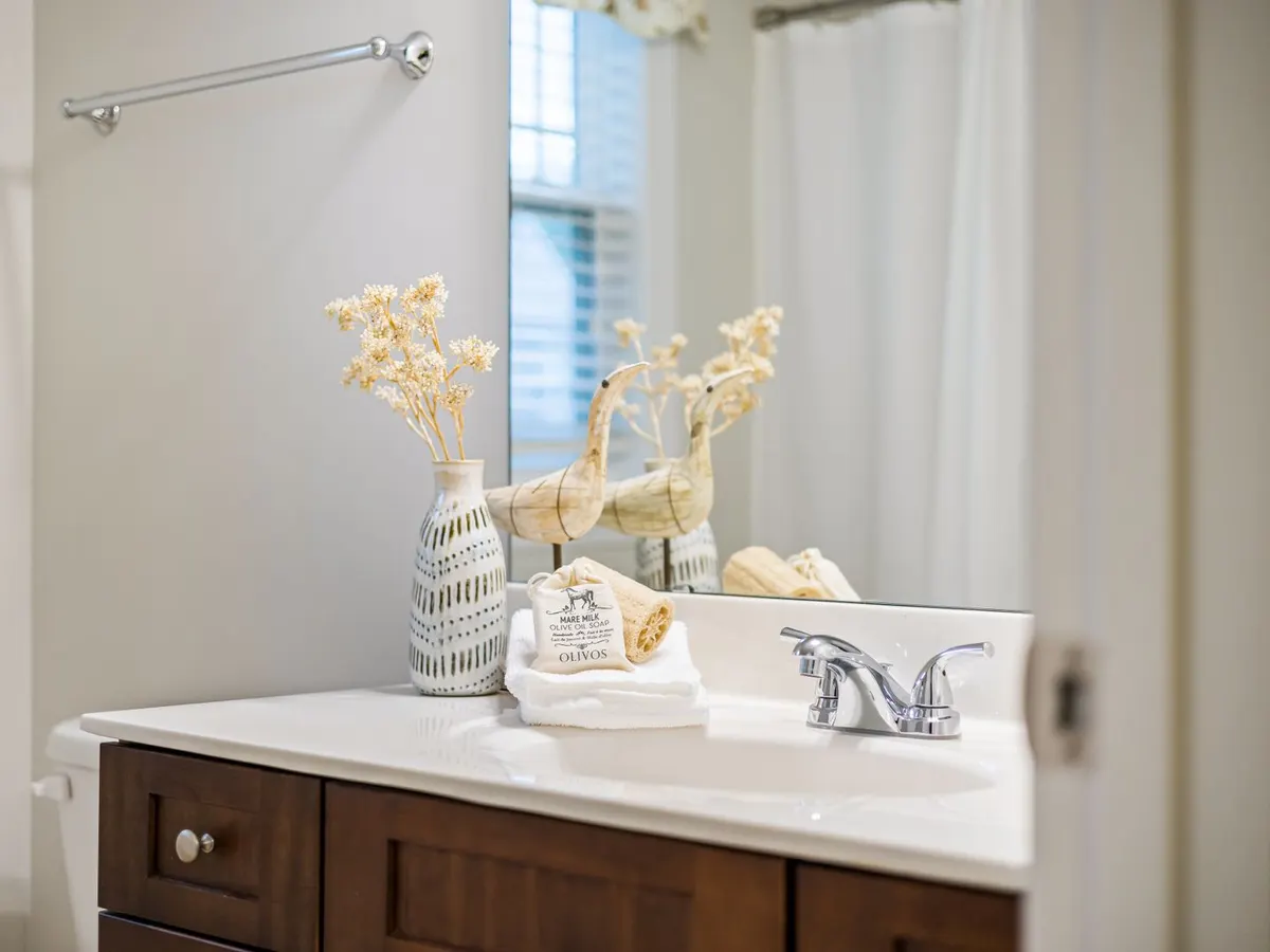 Walnut-stained bathroom vanity with a white countertop and chrome faucet