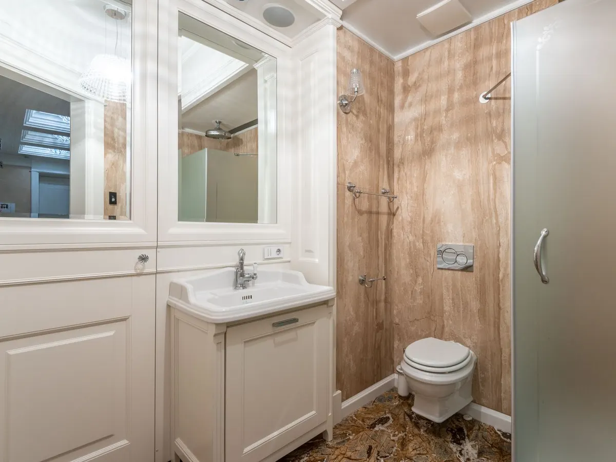 White bathroom vanity with framed mirror beside a wood look shower surround
