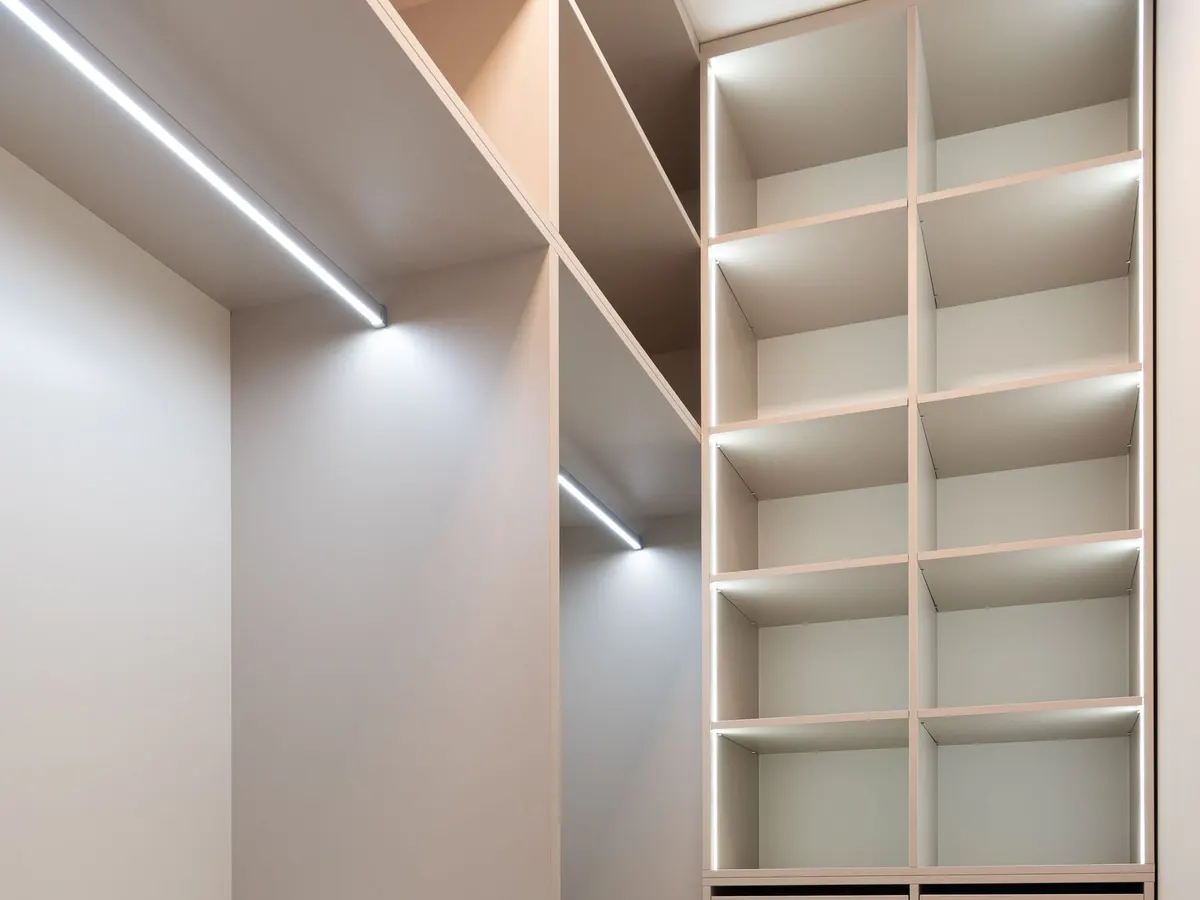 White built-in storage with lighted shelving and a bank of drawers