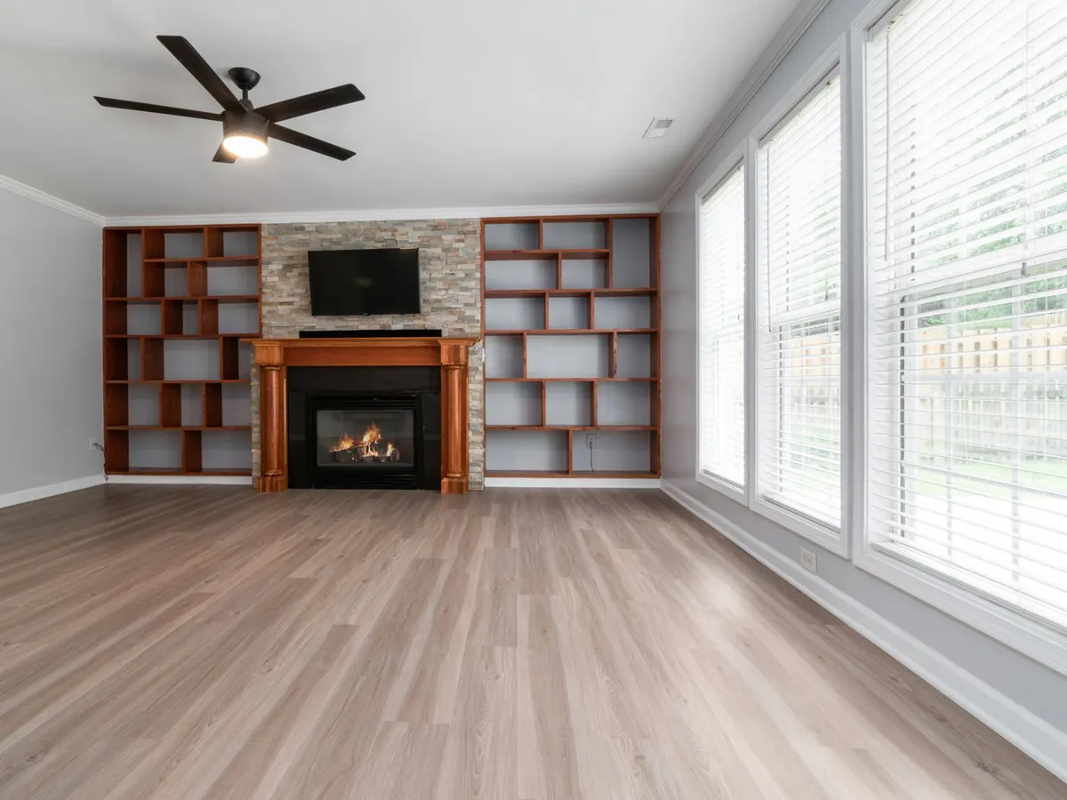 Geometric built-in wood shelving around a stone fireplace in a bright living room