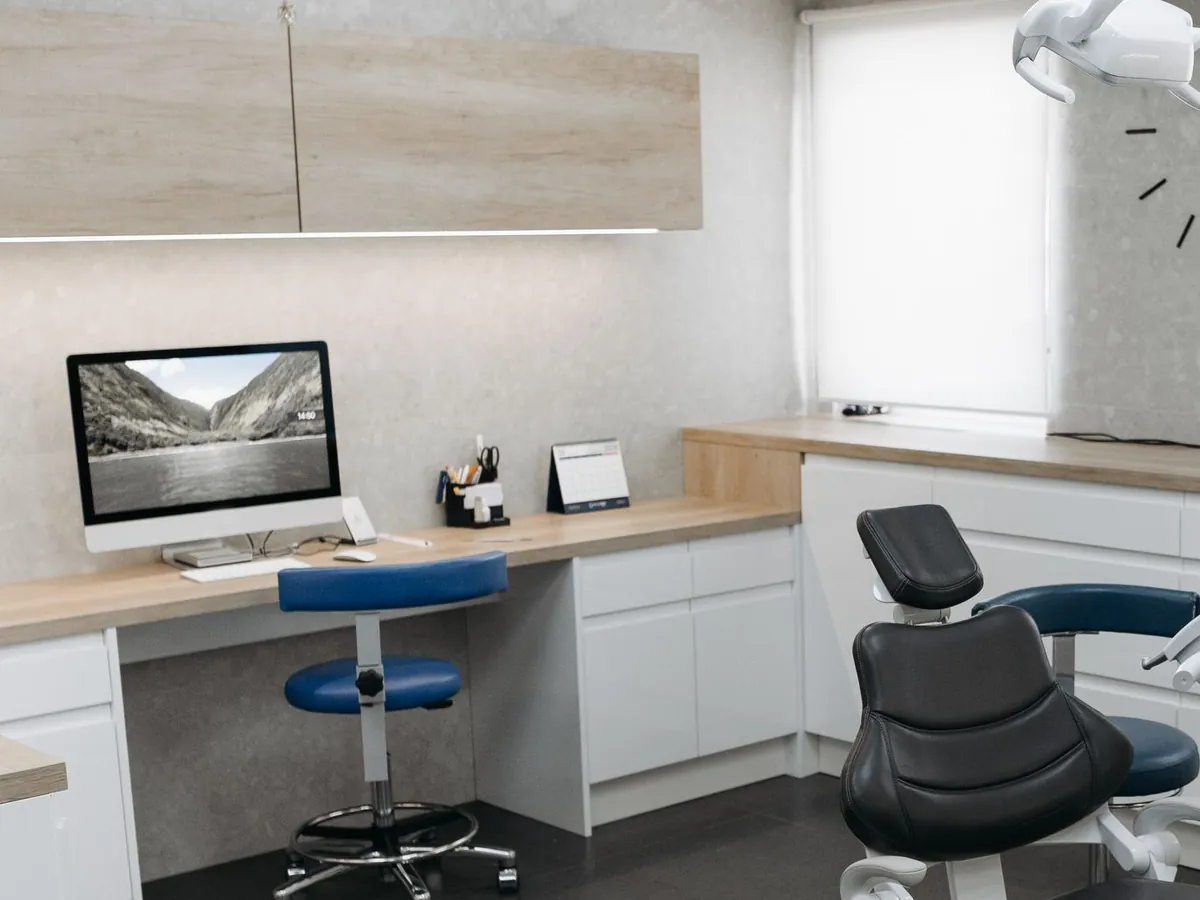 Desk run with white base cabinets under wood-look upper cabinets in a dental operatory