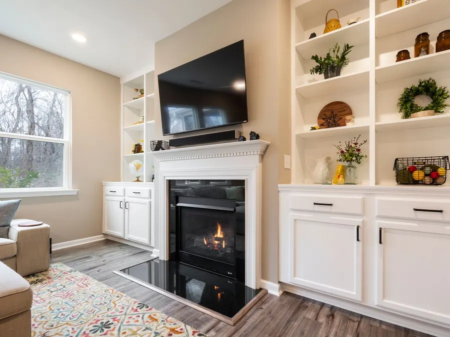 White built-in shelving and cabinets around a fireplace with a mounted television
