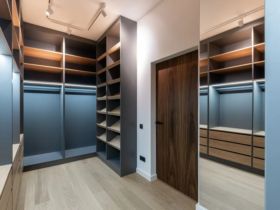 Navy blue walk-in closet cabinets with wood shelving and hanging sections