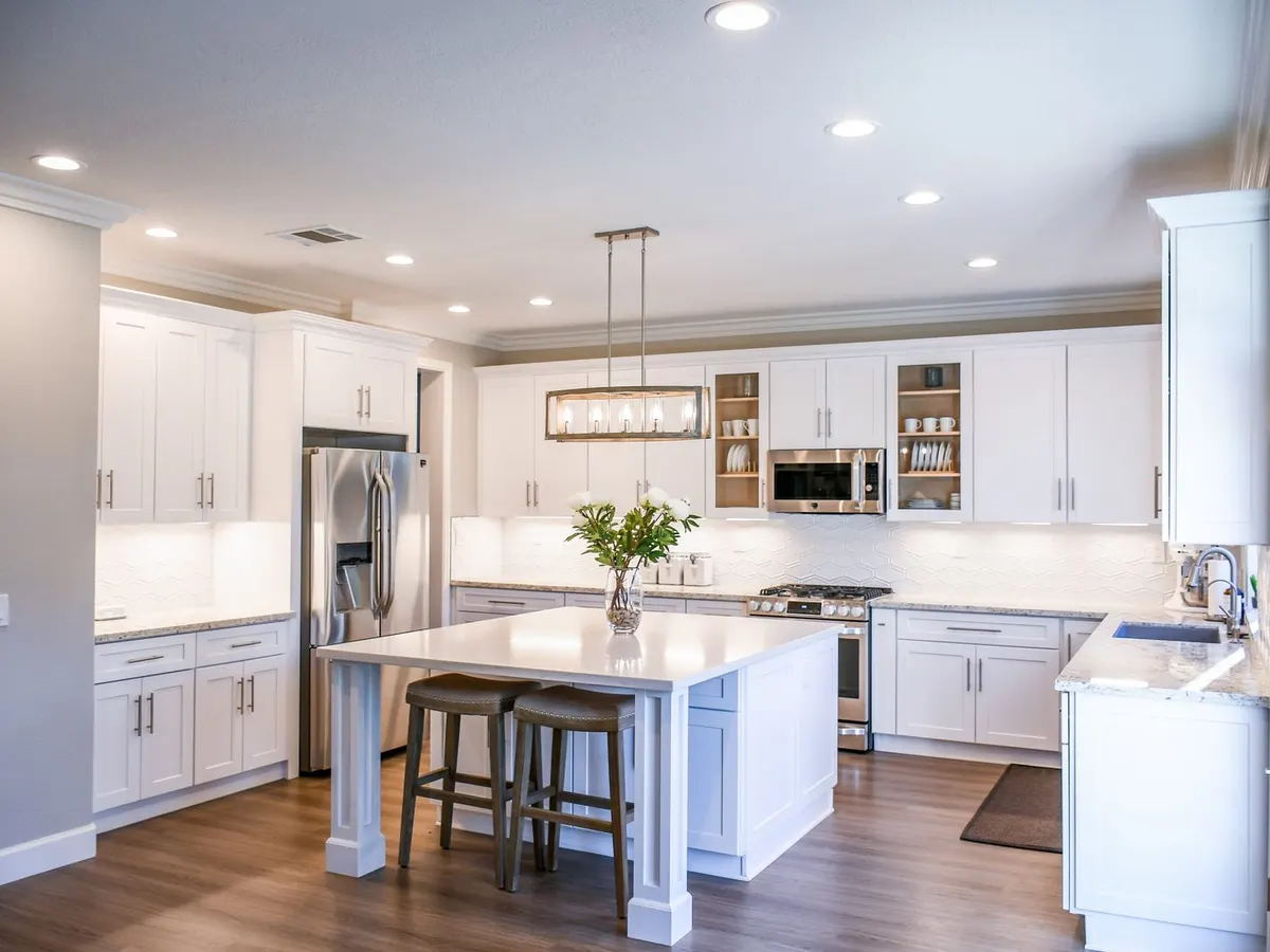White kitchen cabinets with a center island, stainless appliances, and pendant light
