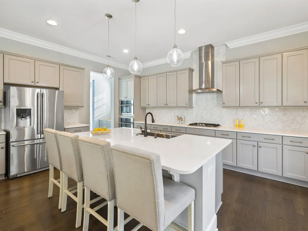 Kitchen island with upholstered stools, pendant lights, and floor to ceiling cabinets