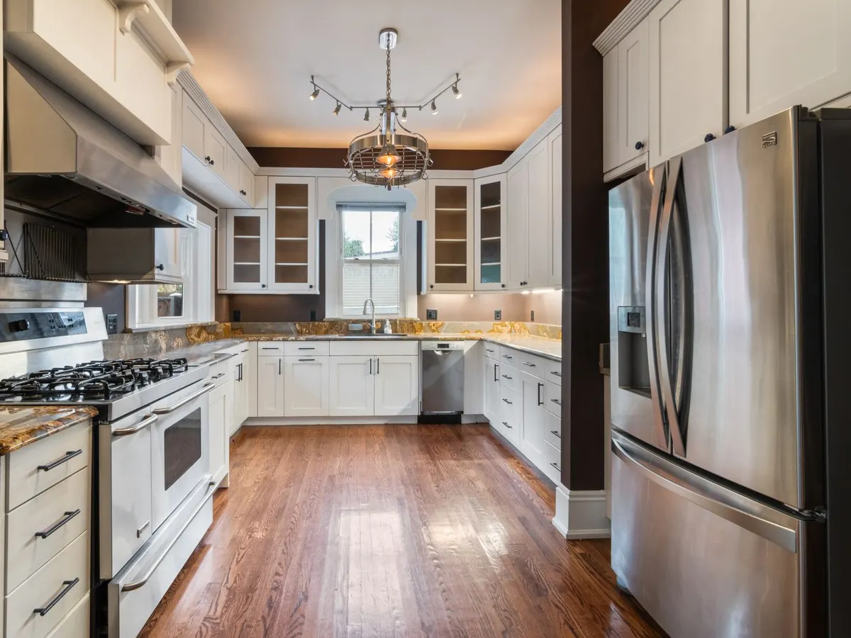 White kitchen with wood floors and a chandelier in an older home