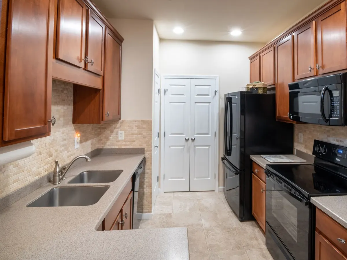 Kitchen with honey oak cabinets and black appliances in a 1990s style