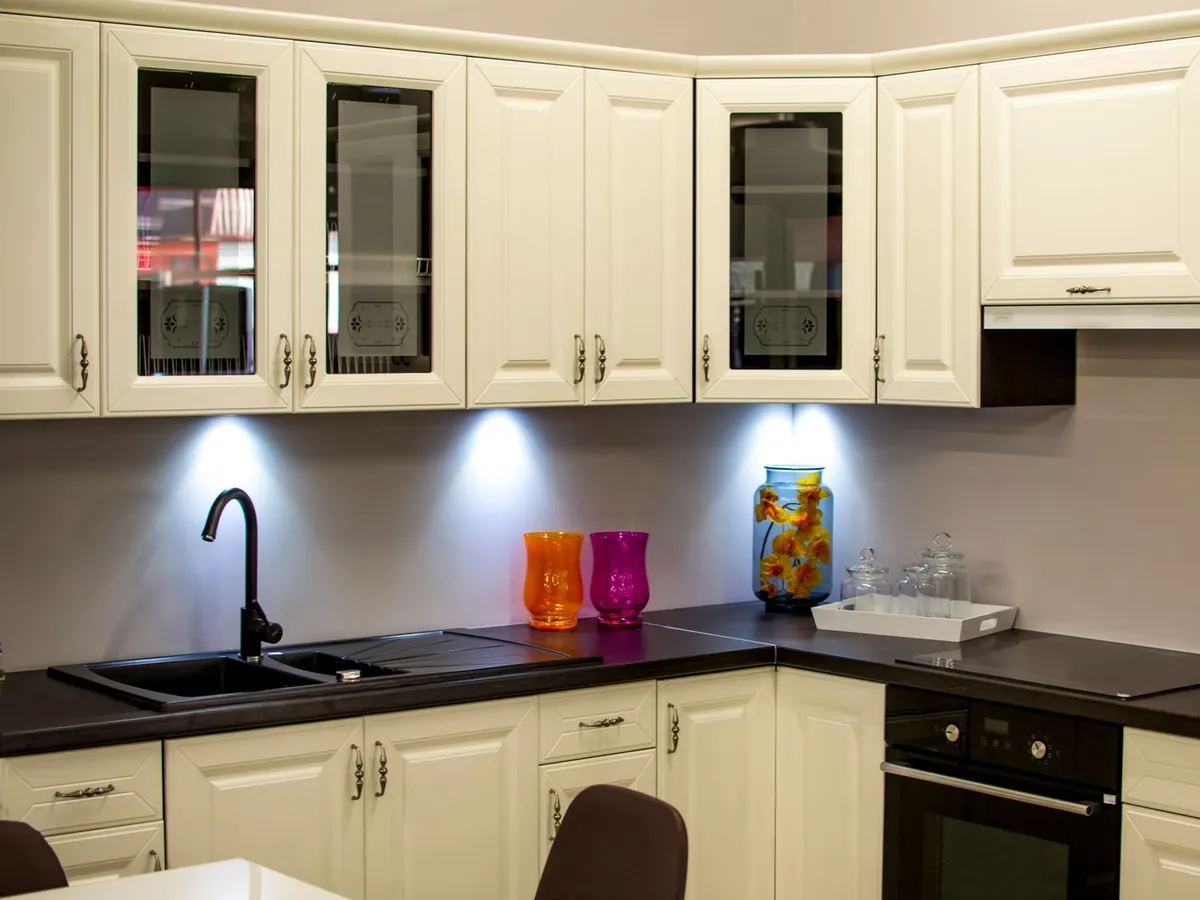 Cream raised panel cabinets with black countertops in a dated kitchen