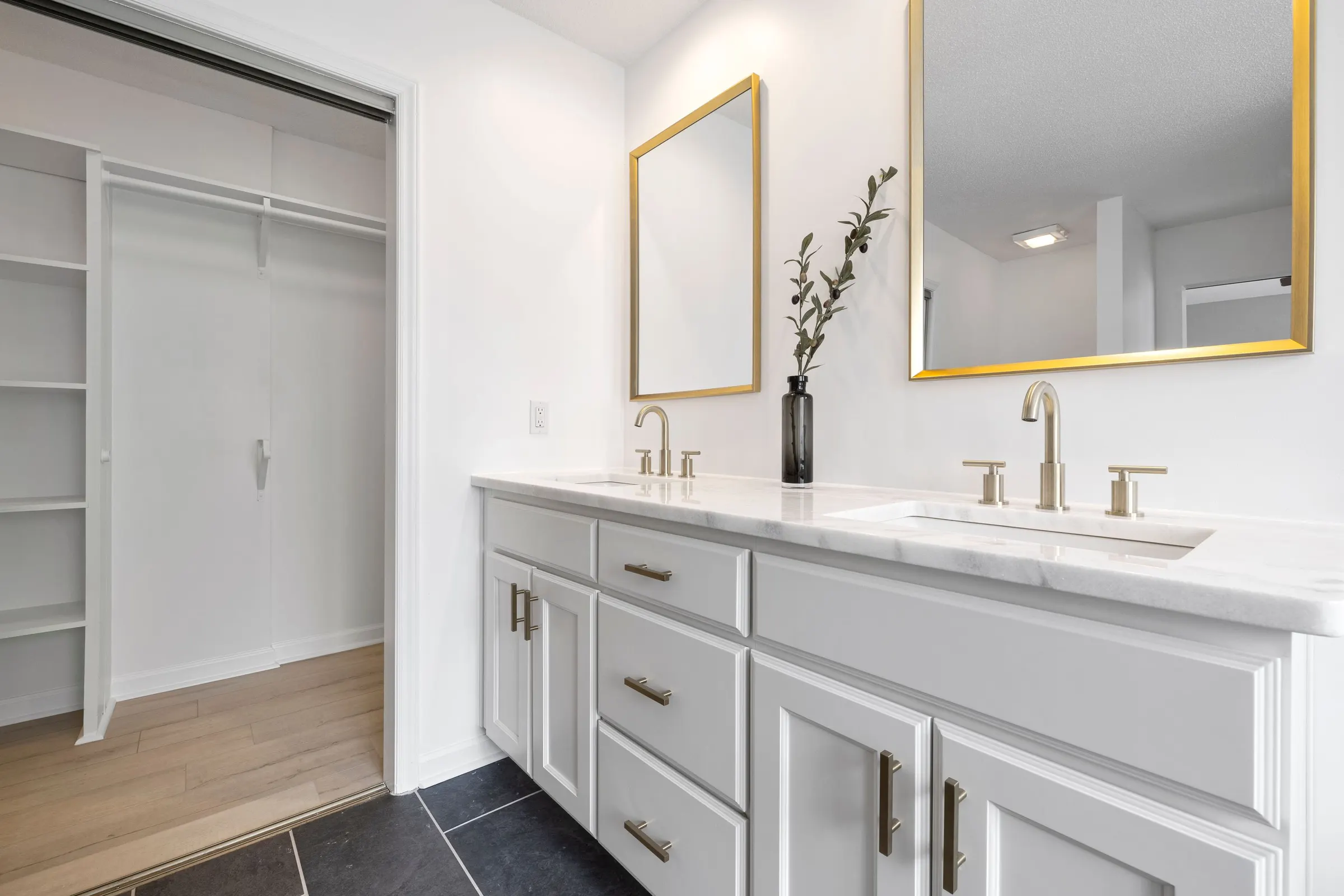 White double vanity with marble countertop and brass framed mirrors