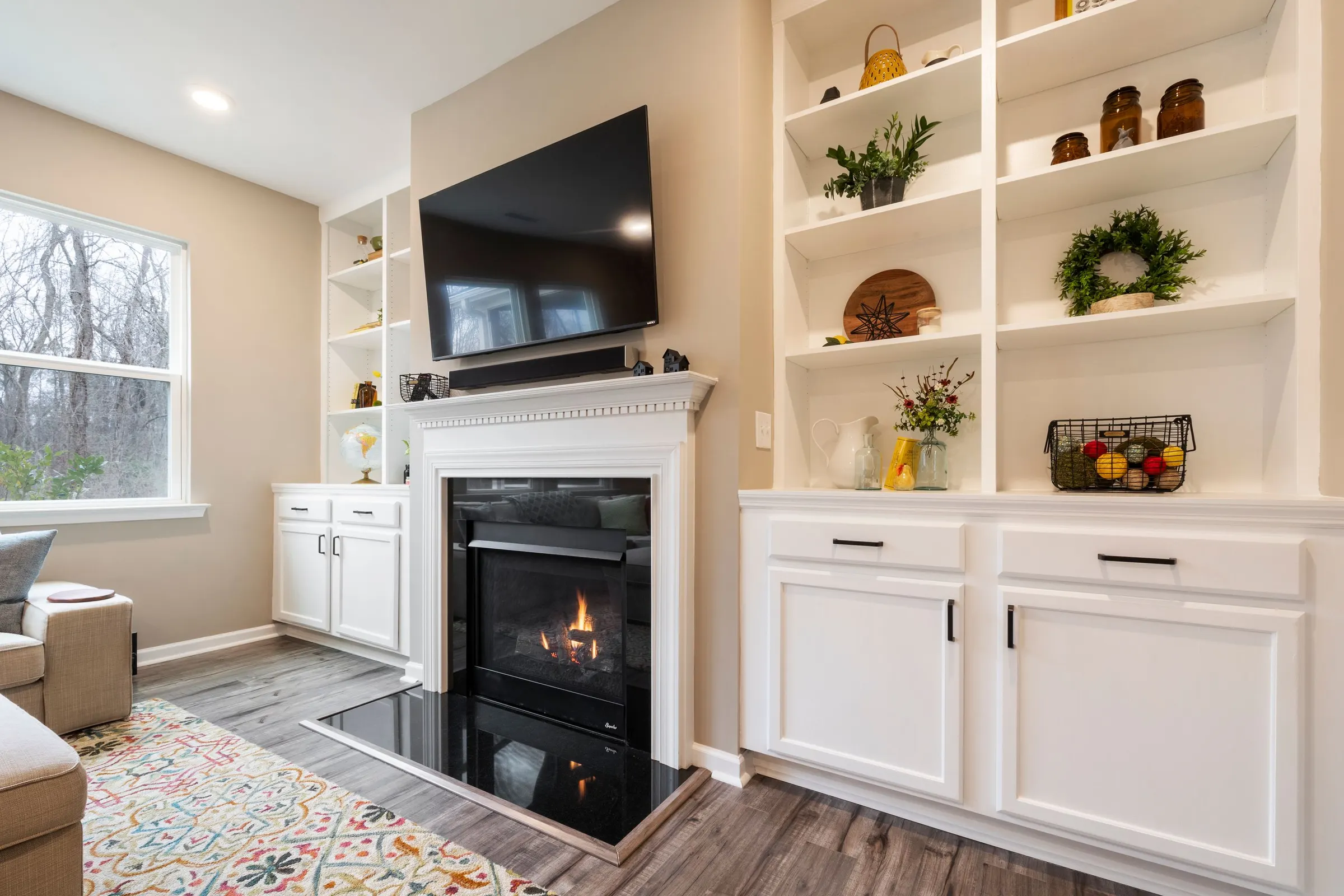 White built-in cabinets and shelving flanking a fireplace with a mounted television