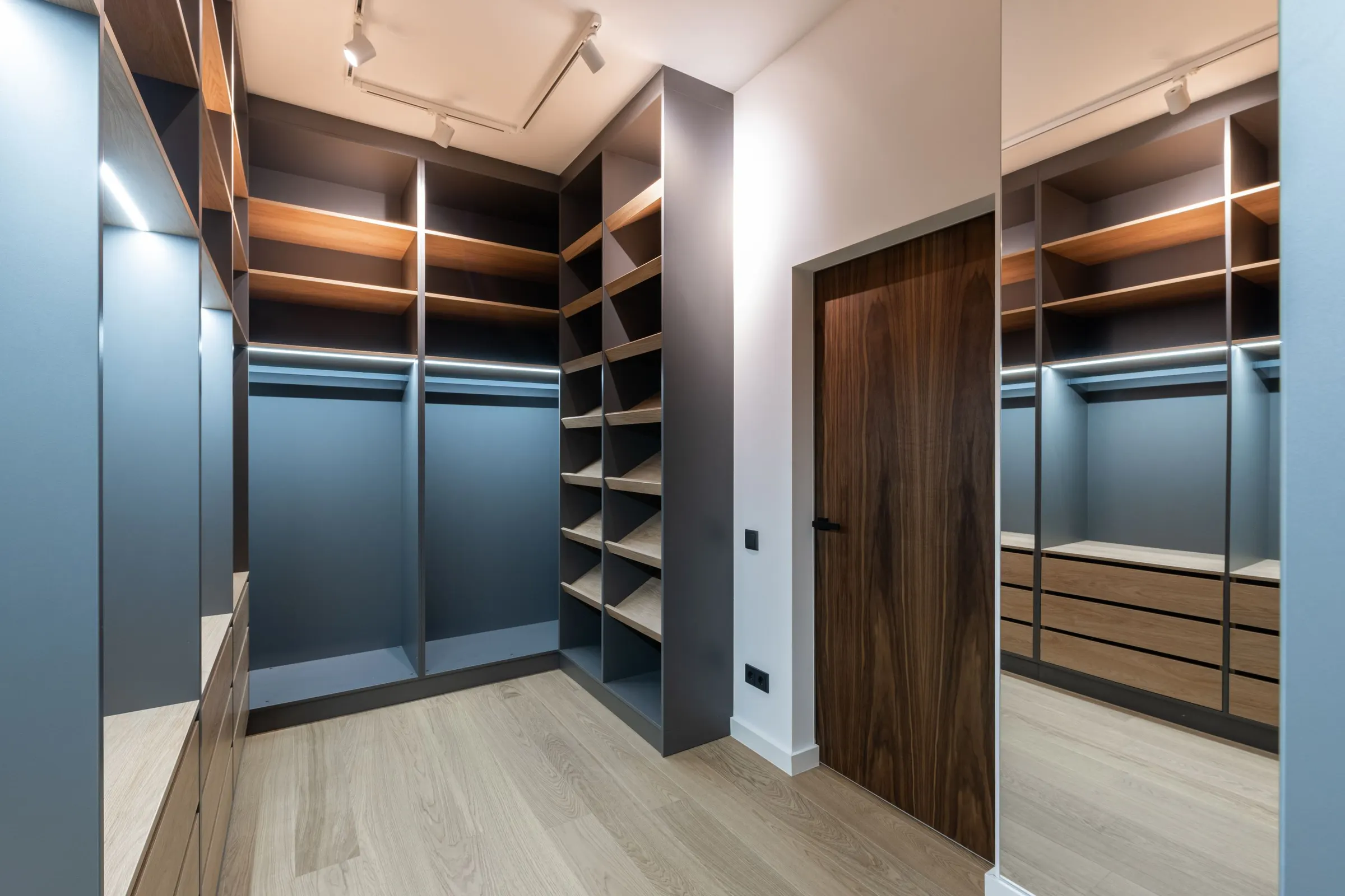 Navy walk-in closet built-ins with wood shelving and hanging sections