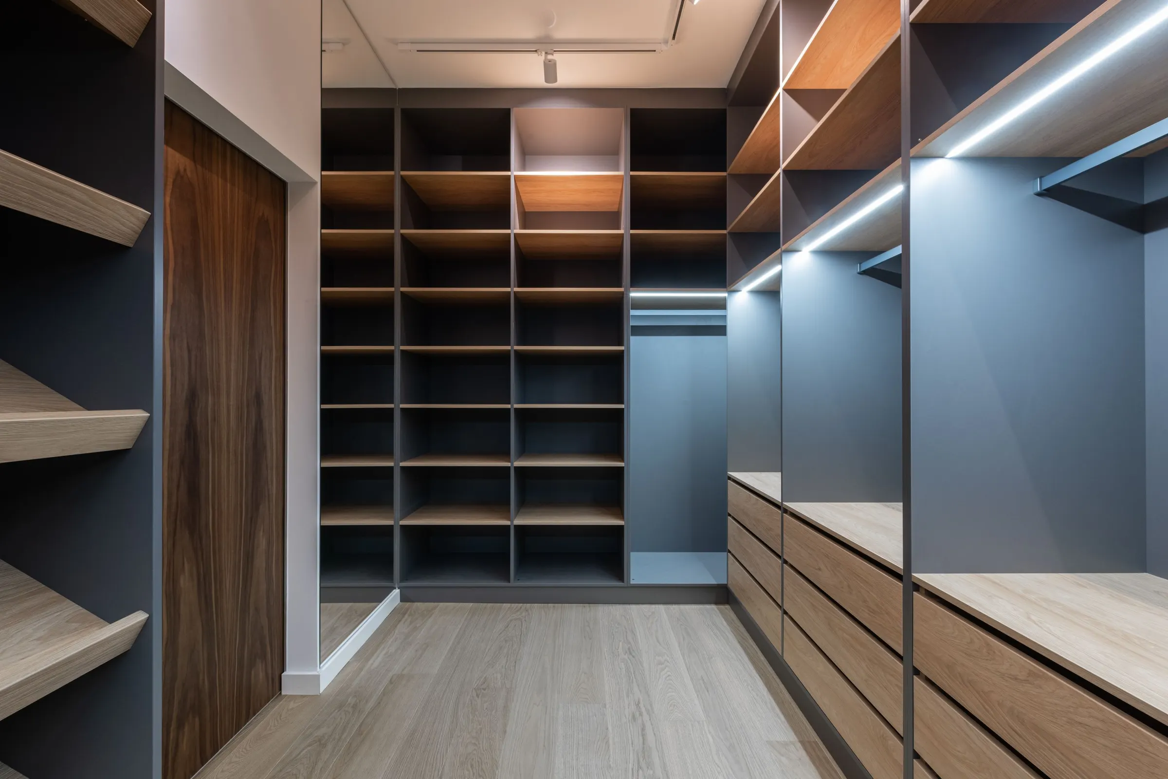 Navy storage cabinets with wood shelving, drawers, and hanging sections