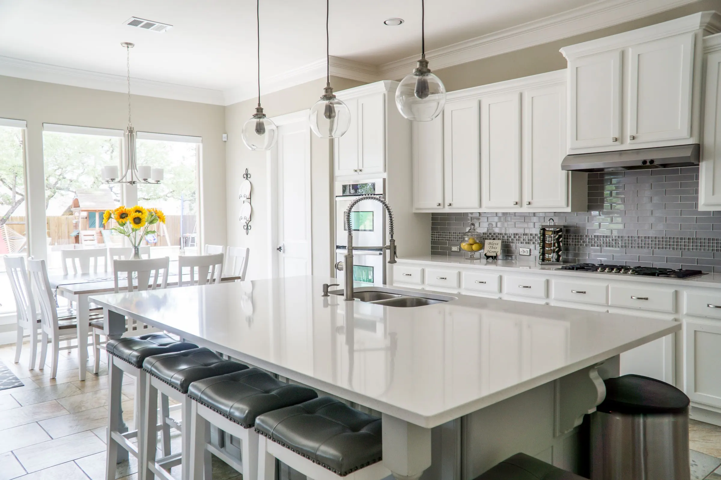Bright kitchen with white custom cabinets and a large island under pendant lighting