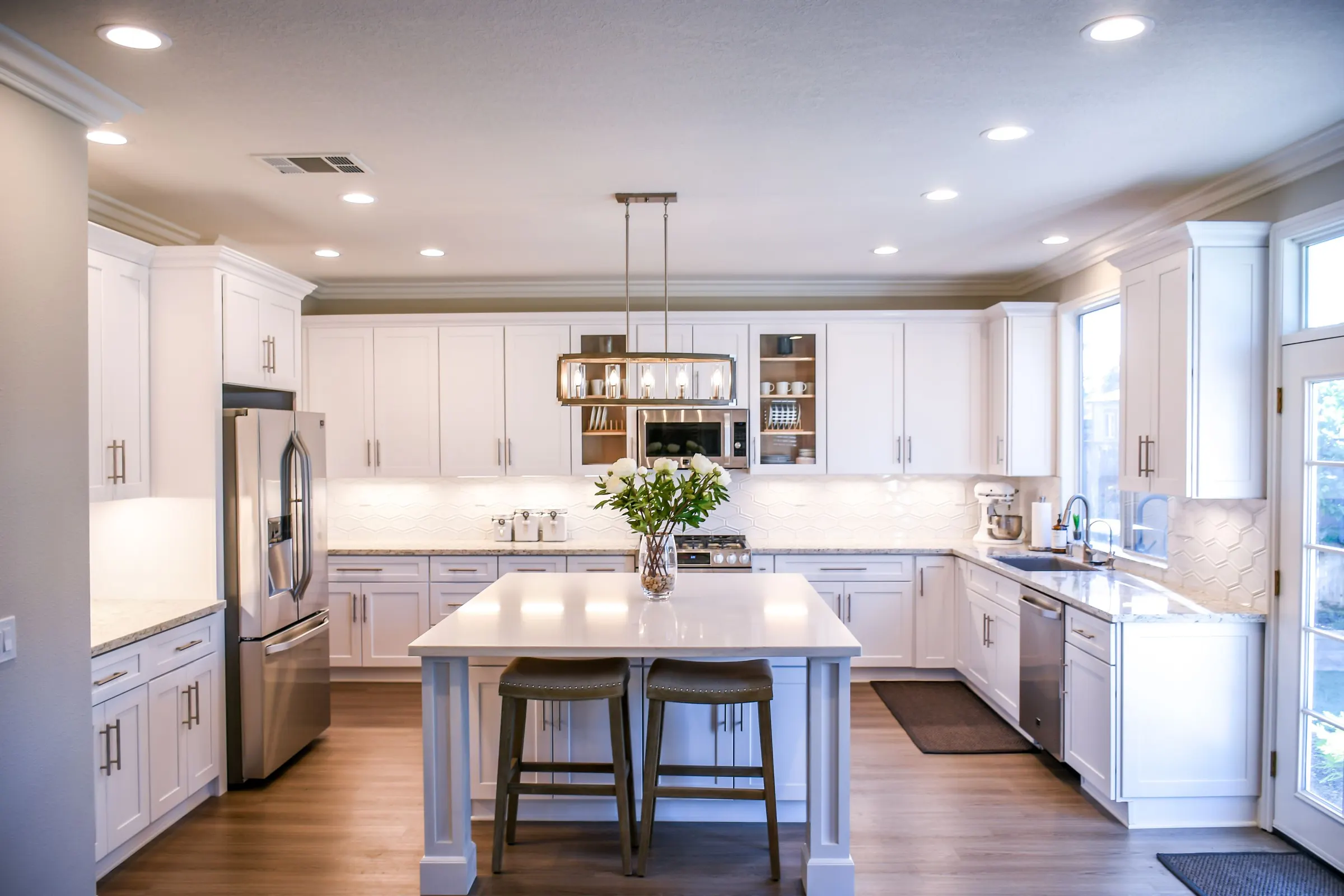 White shaker kitchen cabinets with a large center island and wood floor
