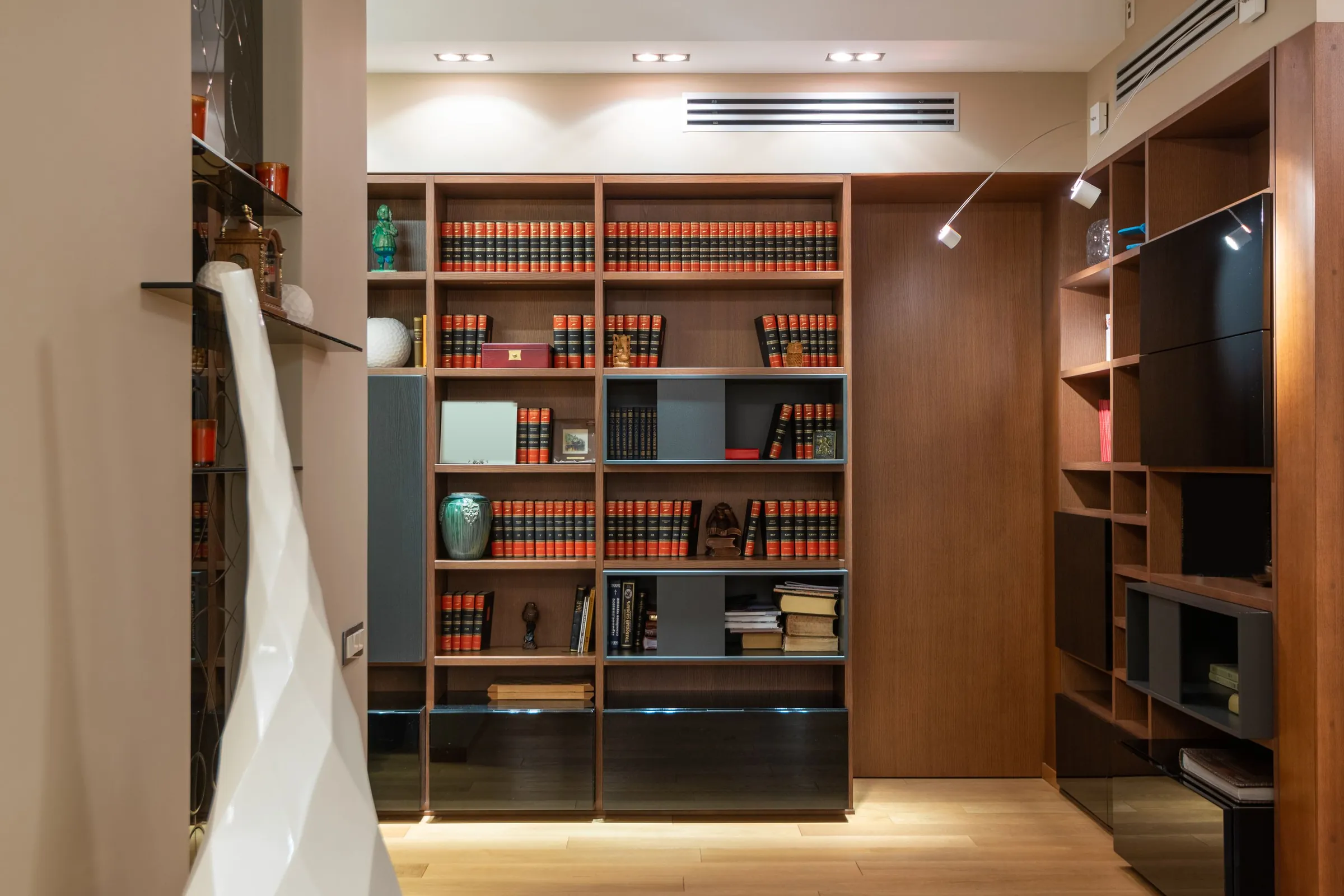Wood built-in library wall with dark lower cabinets and rows of bound volumes