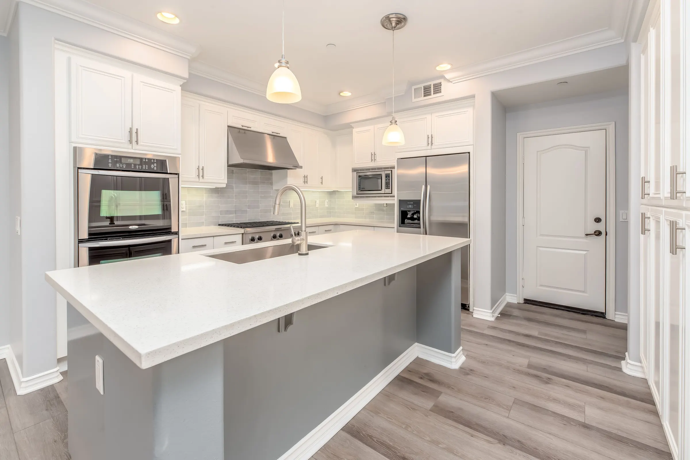 Bright white shaker kitchen with a gray island and pendant light